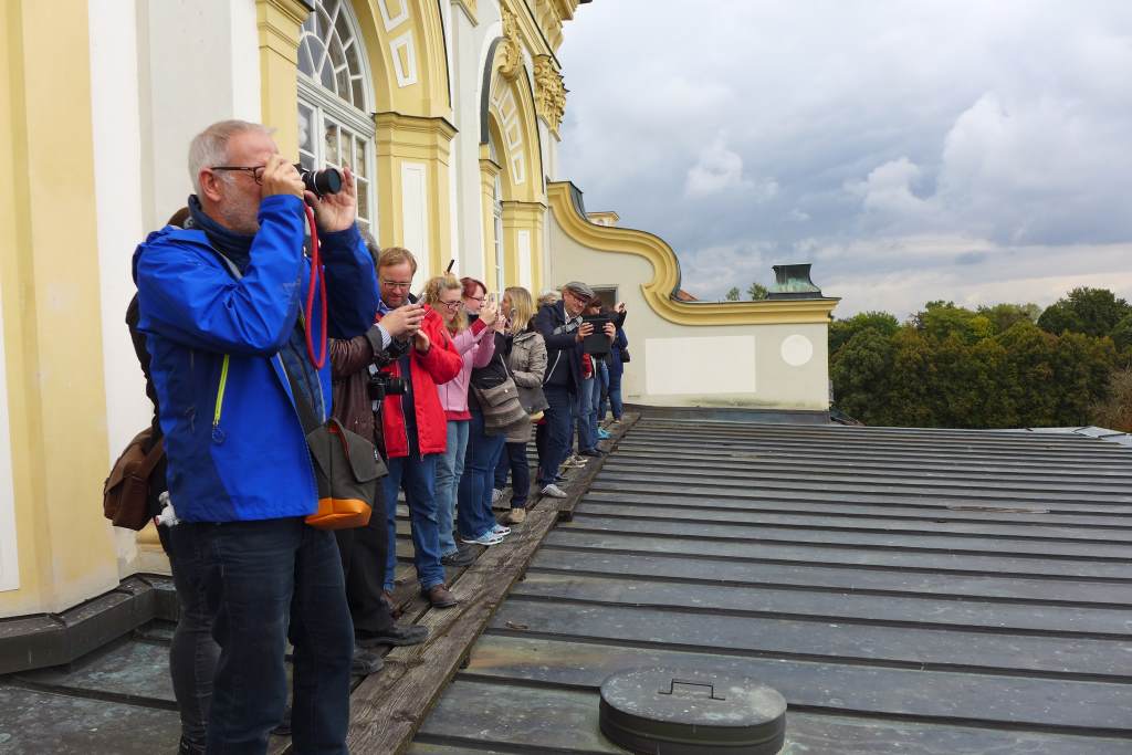 Teilnehmer des Tweetwalks #Lustwandeln auf dem Welldach des Neuen Schlosses Schleißheims. Begeistert fotografiert sie die Aussicht auf den Hofgarten.