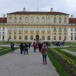 Ansicht des Neuen Schlosses Schleißheim. Davor stehen Teilnehmer des Tweetwalks #Lustwandeln und fotografieren die Umgebung.
