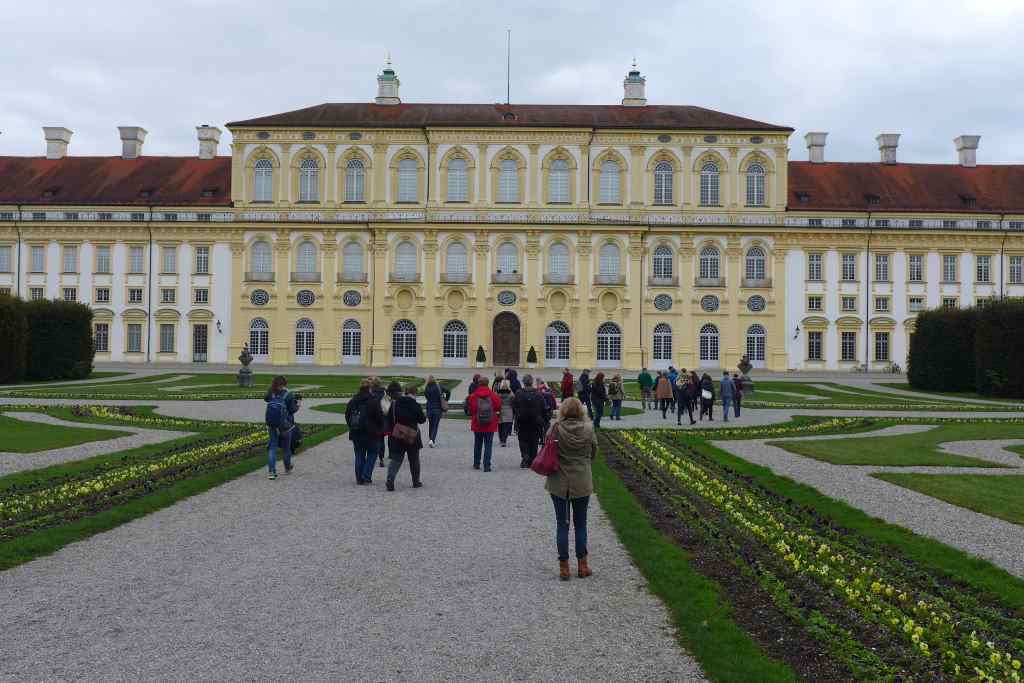 Ansicht des Neuen Schlosses Schleißheim. Davor stehen Teilnehmer des Tweetwalks #Lustwandeln und fotografieren die Umgebung.